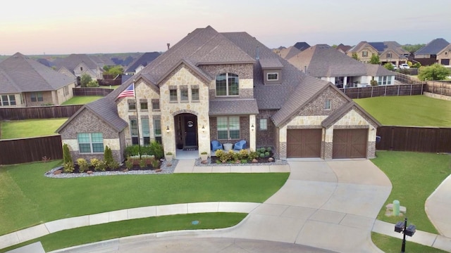 french country style house with driveway, stone siding, fence, and a front lawn