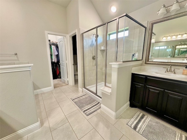 bathroom with a spacious closet, a stall shower, vanity, tile patterned flooring, and baseboards