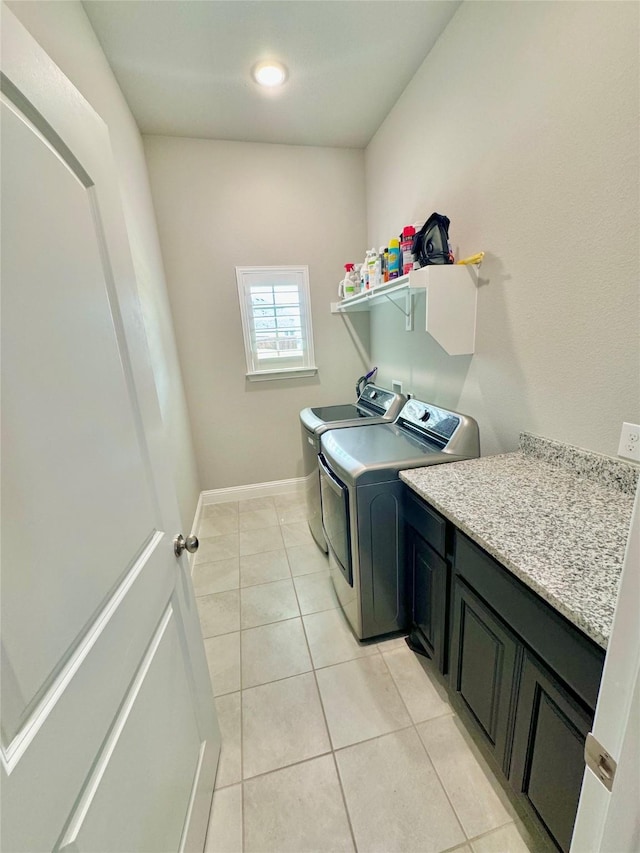 laundry area featuring light tile patterned floors, washer and clothes dryer, cabinet space, and baseboards