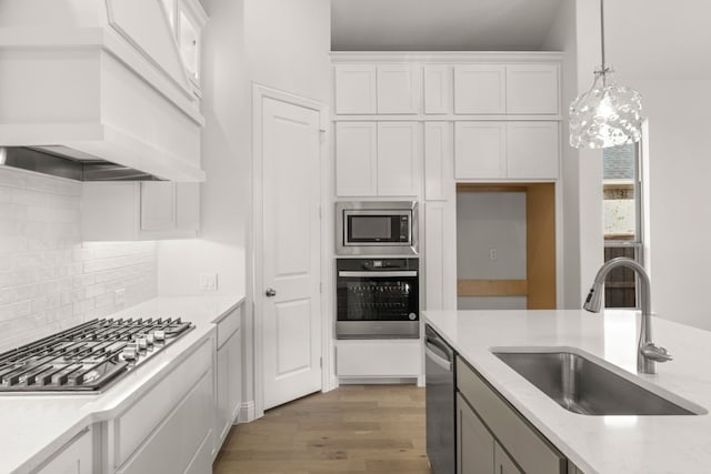 kitchen with dark wood-style floors, pendant lighting, stainless steel appliances, white cabinetry, and a sink