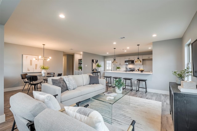 living room featuring light wood-style flooring, visible vents, baseboards, and recessed lighting