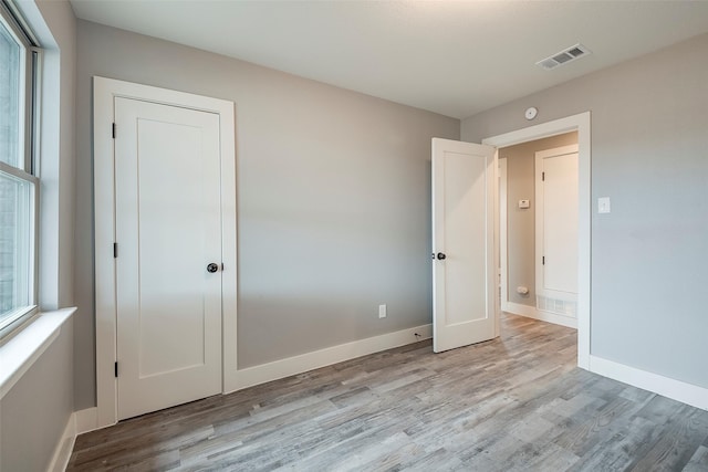 unfurnished bedroom with light wood-type flooring, visible vents, and baseboards