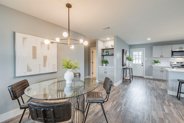 dining room featuring baseboards, visible vents, light wood-style floors, a notable chandelier, and recessed lighting