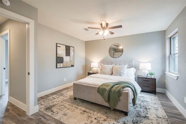 bedroom with dark wood-style floors, visible vents, baseboards, and ceiling fan