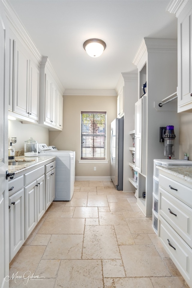 laundry area featuring baseboards, independent washer and dryer, stone tile flooring, and crown molding