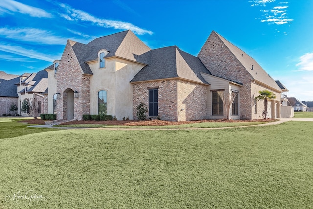 french provincial home featuring a front lawn, a garage, brick siding, and roof with shingles