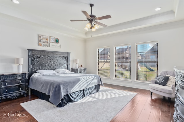 bedroom featuring a tray ceiling, recessed lighting, crown molding, and dark wood-type flooring