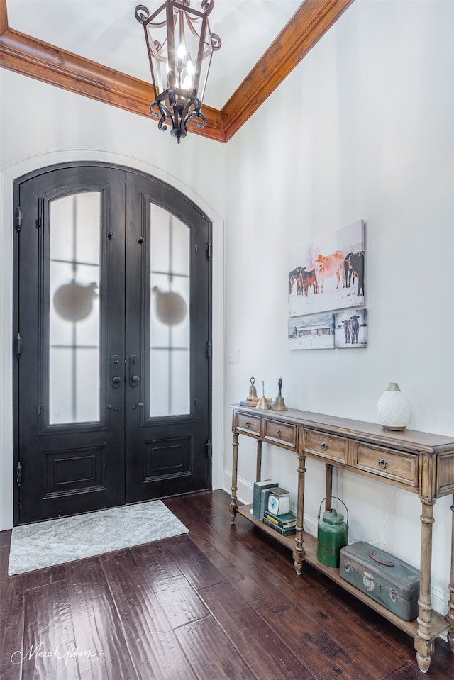 foyer entrance with arched walkways, ornamental molding, hardwood / wood-style flooring, french doors, and a notable chandelier