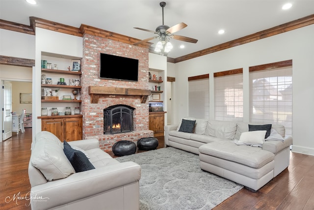 living area featuring built in shelves, wood finished floors, a fireplace, and crown molding