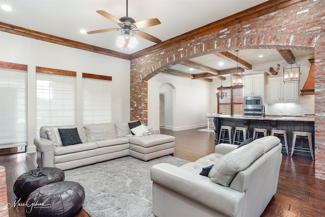 living area featuring dark wood-type flooring, beamed ceiling, baseboards, and arched walkways