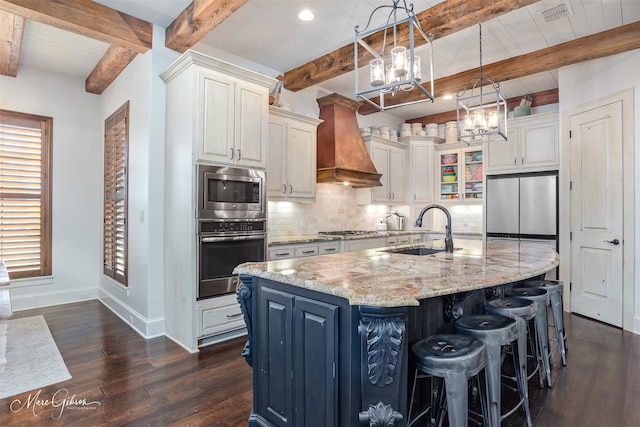 kitchen featuring baseboards, decorative backsplash, appliances with stainless steel finishes, custom exhaust hood, and a sink