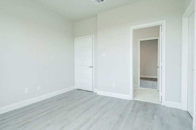 unfurnished bedroom with visible vents, light wood-style flooring, and baseboards