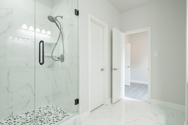 bathroom featuring marble finish floor, a marble finish shower, and baseboards