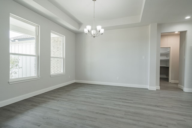 unfurnished room with wood finished floors, a raised ceiling, and baseboards