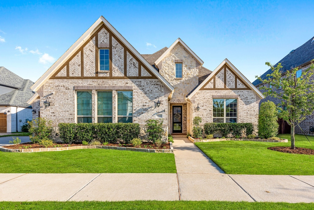 tudor house with stone siding, brick siding, and a front lawn