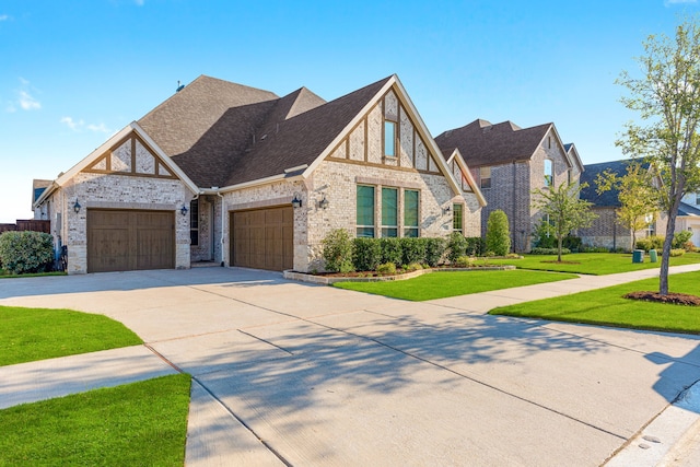 view of front facade featuring roof with shingles, brick siding, an attached garage, a front yard, and driveway