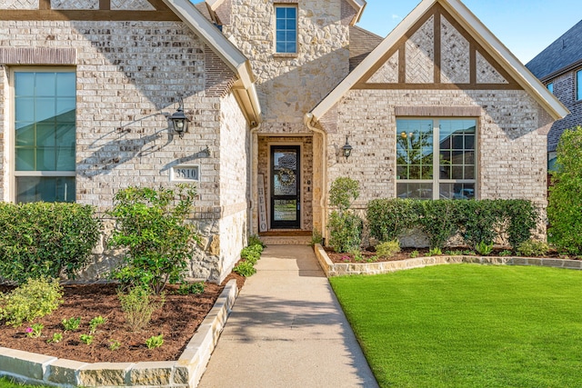 entrance to property featuring a yard, stone siding, and brick siding