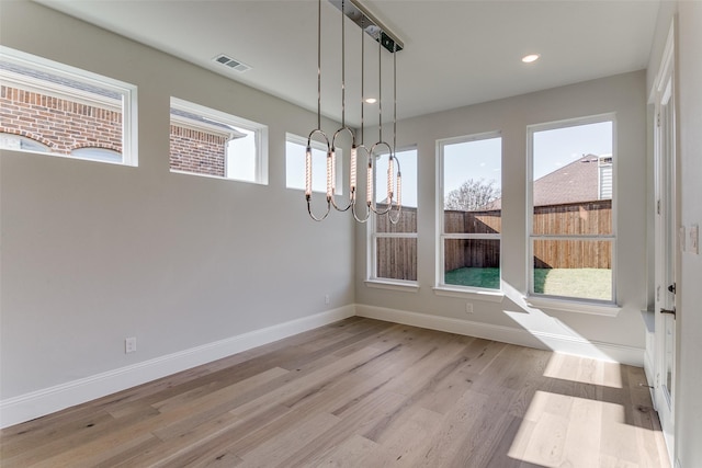 unfurnished dining area featuring recessed lighting, visible vents, baseboards, light wood-type flooring, and an inviting chandelier