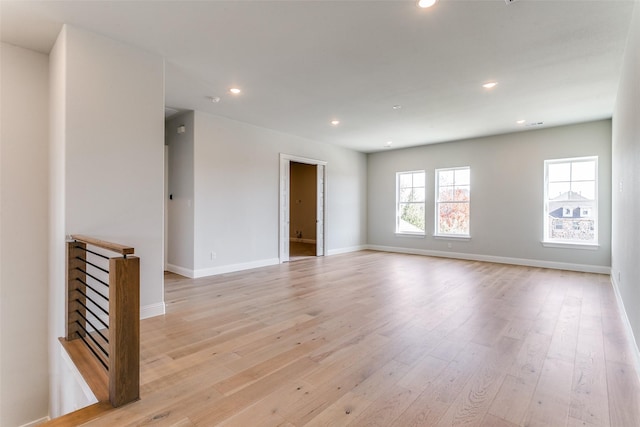 empty room featuring baseboards, light wood-type flooring, and recessed lighting