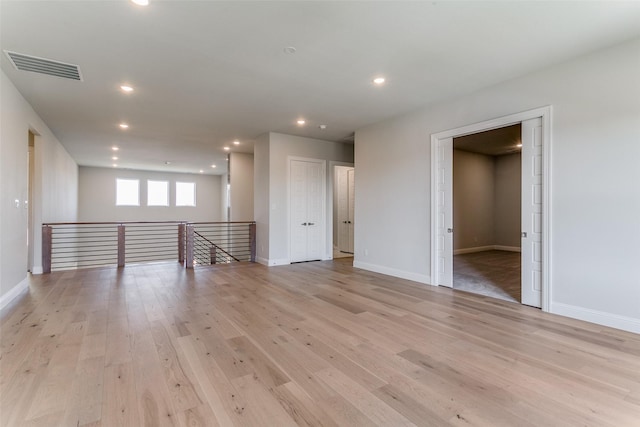 empty room featuring light wood-style floors, recessed lighting, visible vents, and baseboards