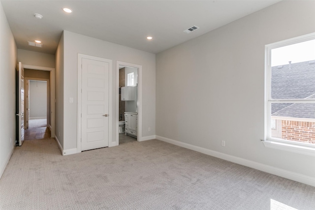 unfurnished bedroom with visible vents, baseboards, light colored carpet, ensuite bath, and recessed lighting