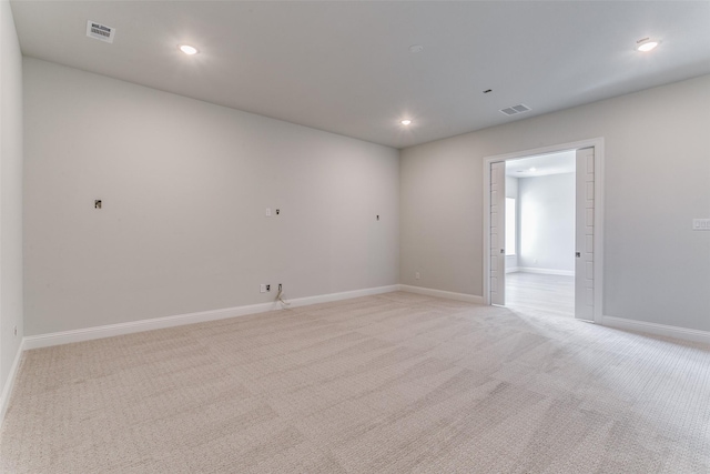 spare room with light carpet, recessed lighting, visible vents, and baseboards