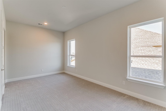 unfurnished room featuring light colored carpet, visible vents, baseboards, and recessed lighting