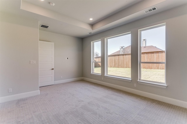 spare room featuring recessed lighting, light colored carpet, visible vents, baseboards, and a tray ceiling