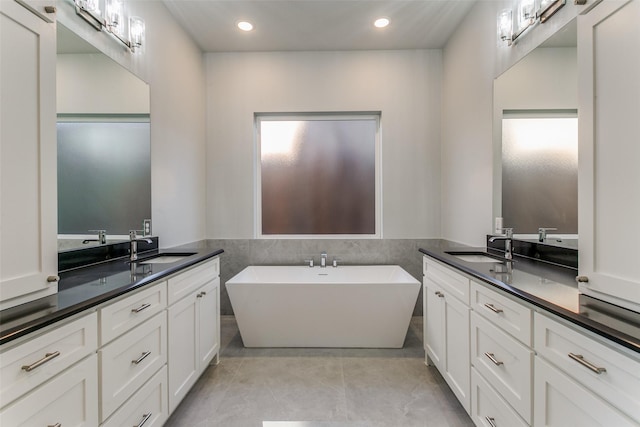 full bath with wainscoting, a soaking tub, vanity, tile walls, and recessed lighting