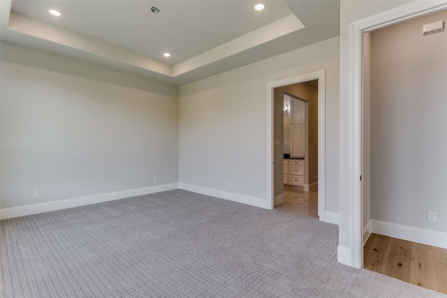 unfurnished bedroom featuring ensuite bathroom, recessed lighting, carpet floors, baseboards, and a tray ceiling