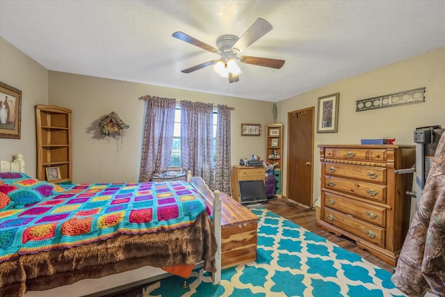 bedroom with a textured ceiling, wood finished floors, and a ceiling fan