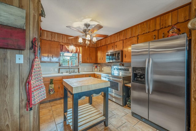 kitchen with brown cabinetry, light tile patterned floors, stainless steel appliances, and light countertops