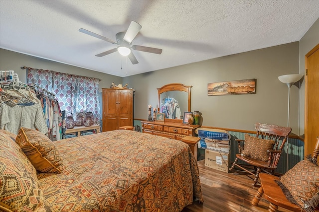 bedroom with a ceiling fan, a textured ceiling, and wood finished floors