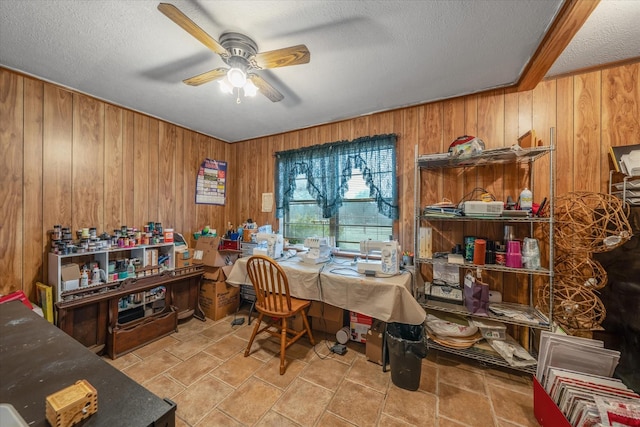 dining space with wood walls, a ceiling fan, and a textured ceiling