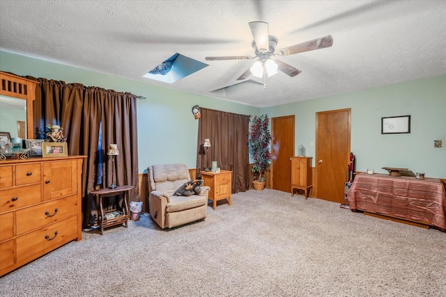 living area featuring a textured ceiling, a skylight, a ceiling fan, and light colored carpet