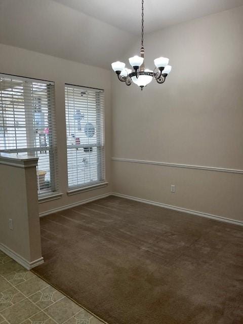 empty room with lofted ceiling, baseboards, dark colored carpet, and a notable chandelier