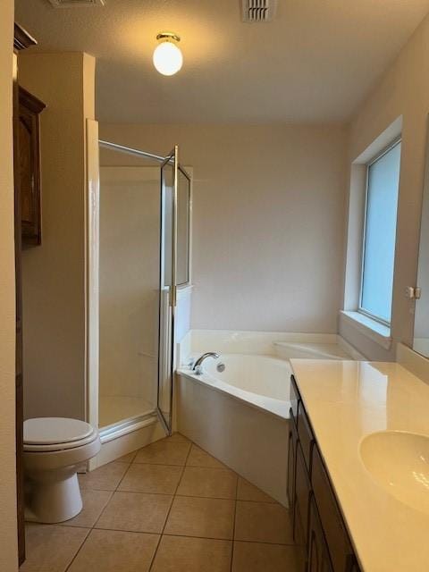 full bathroom featuring a stall shower, toilet, tile patterned floors, a garden tub, and vanity