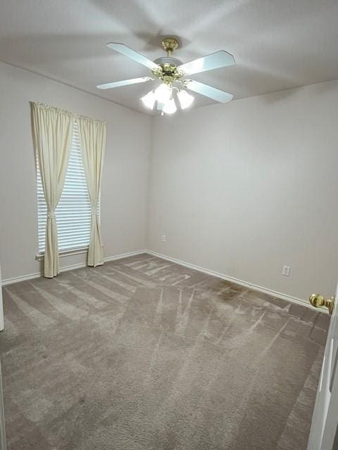 carpeted empty room with a ceiling fan and baseboards