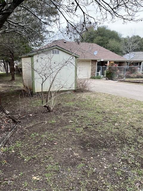 view of front facade featuring concrete driveway, an attached garage, and fence