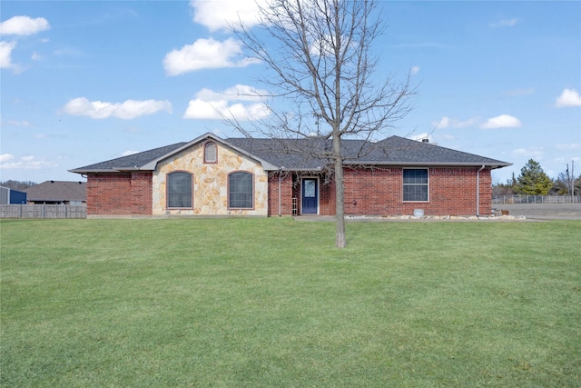 ranch-style house featuring a shingled roof, stone siding, fence, a front lawn, and brick siding