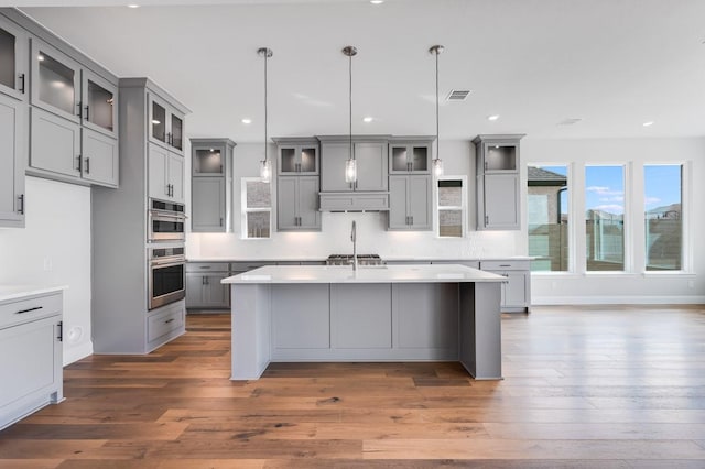 kitchen with visible vents, gray cabinetry, and an island with sink