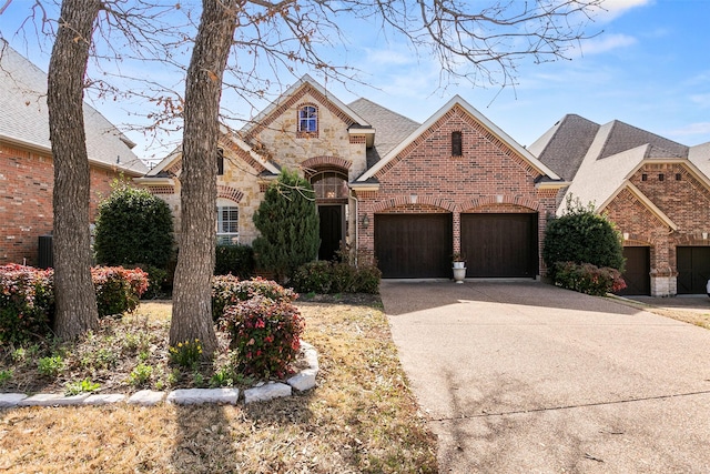 view of front of property with stone siding, a garage, brick siding, and driveway