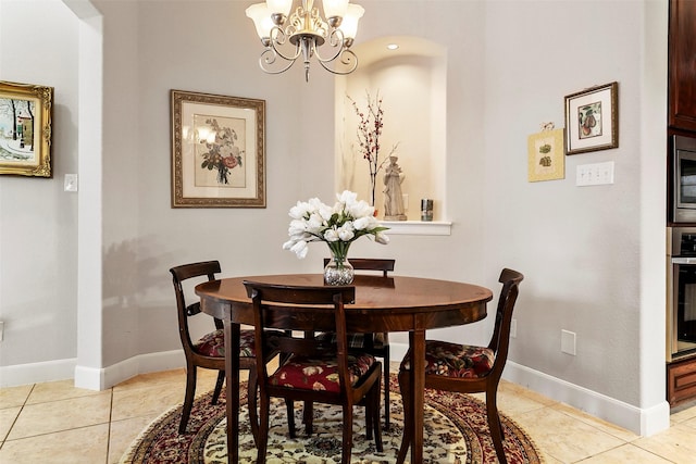 dining area featuring light tile patterned floors, baseboards, and a chandelier