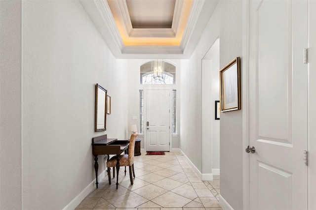 foyer featuring baseboards, a chandelier, a tray ceiling, ornamental molding, and light tile patterned flooring