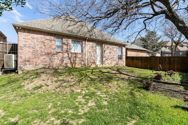 rear view of house featuring brick siding, central air condition unit, a yard, and fence