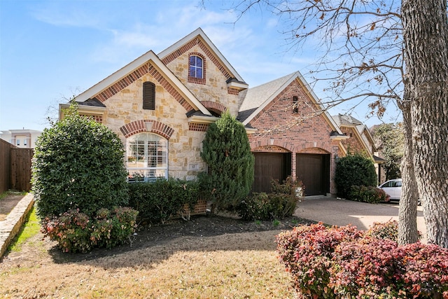 view of front of property with a garage, stone siding, brick siding, and driveway