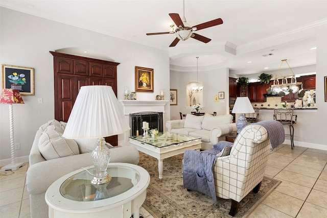 living area with light tile patterned floors, baseboards, ornamental molding, and ceiling fan with notable chandelier