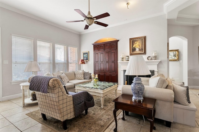 living area with arched walkways, a fireplace, crown molding, baseboards, and ceiling fan