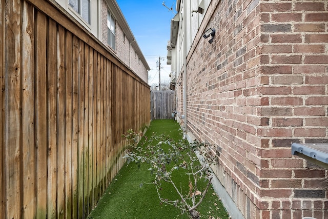 view of property exterior with brick siding and fence