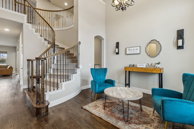 interior space with arched walkways, wood finished floors, a towering ceiling, baseboards, and stairs